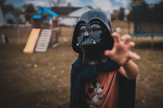 Child on a playground wearing Darth Vader mask.