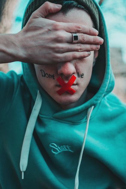 Man in teal hoodie with Dont Lie on his mouth.
