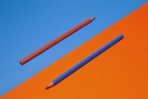 A red pencil and blue pencil pointing opposite directions