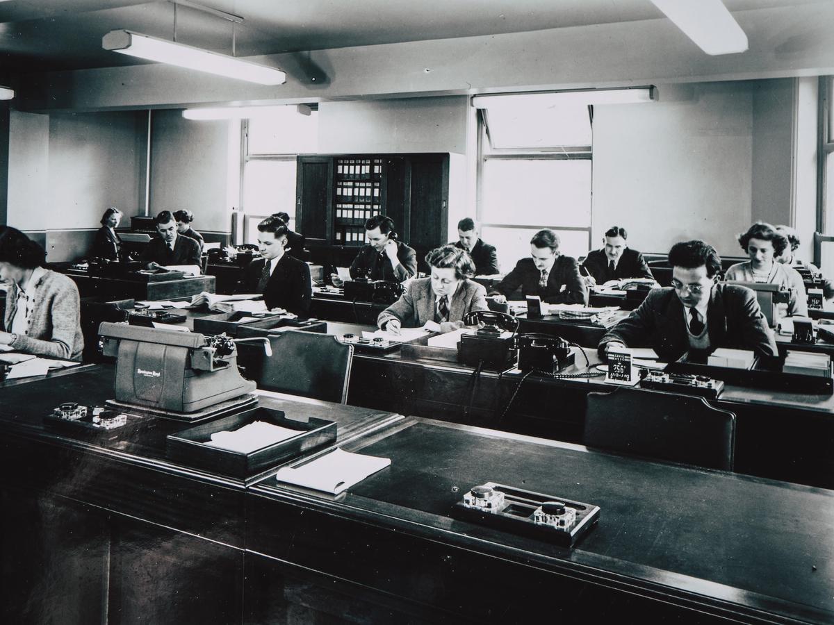 A vintage photograph showing a room filled with workers from 1951.