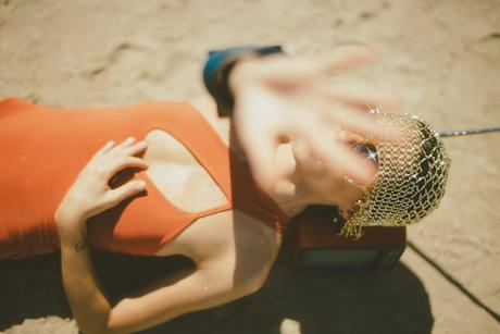 Woman lying on her back, blocking the camera with her hand.