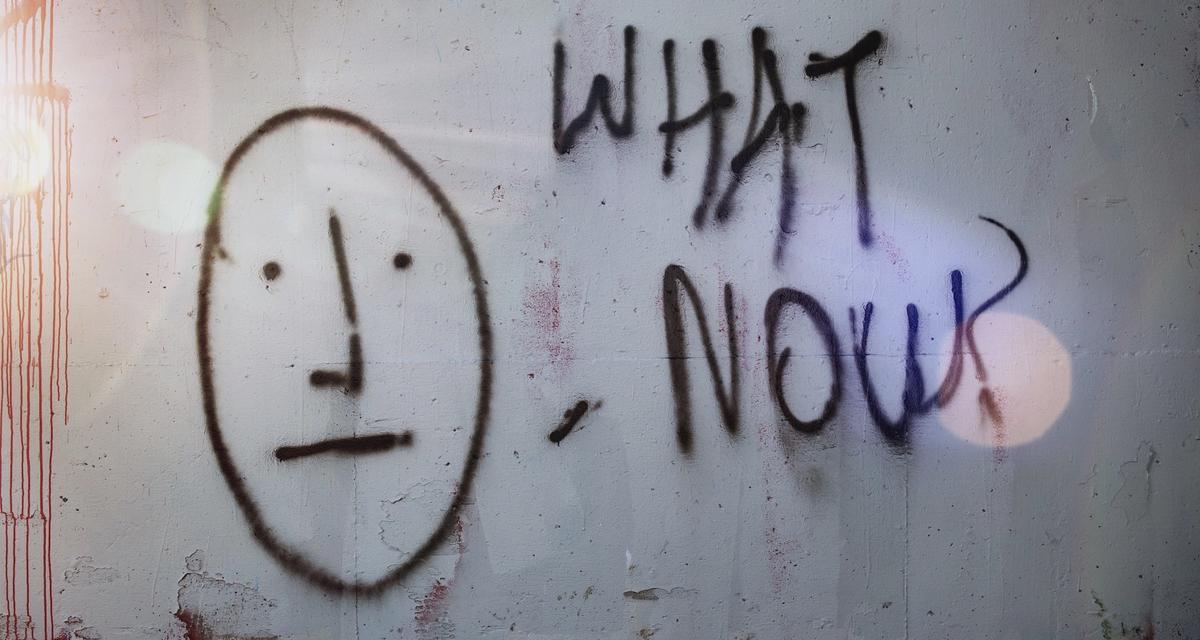 Graffiti of a face and the words 'what now?'